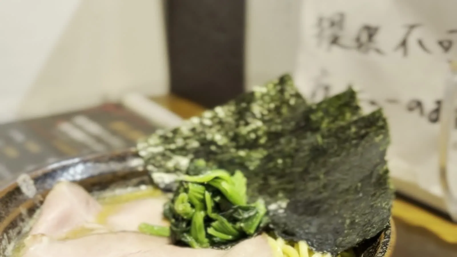 Another angle of the tonkotsu ramen bowl at みなや, showing nori and Japanese writing on wall