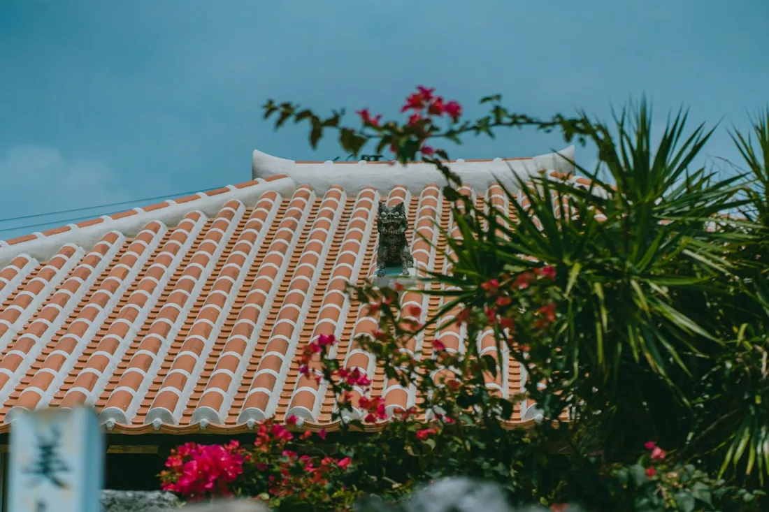 Pink flowers beside a traditional red-tiled roof on Taketomi Island
